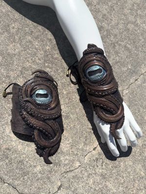Pair of handmade silicone kraken tentacle gauntlets with glowing blue cyclops eyes and adjustable lace-up arm wraps by Mertailor.